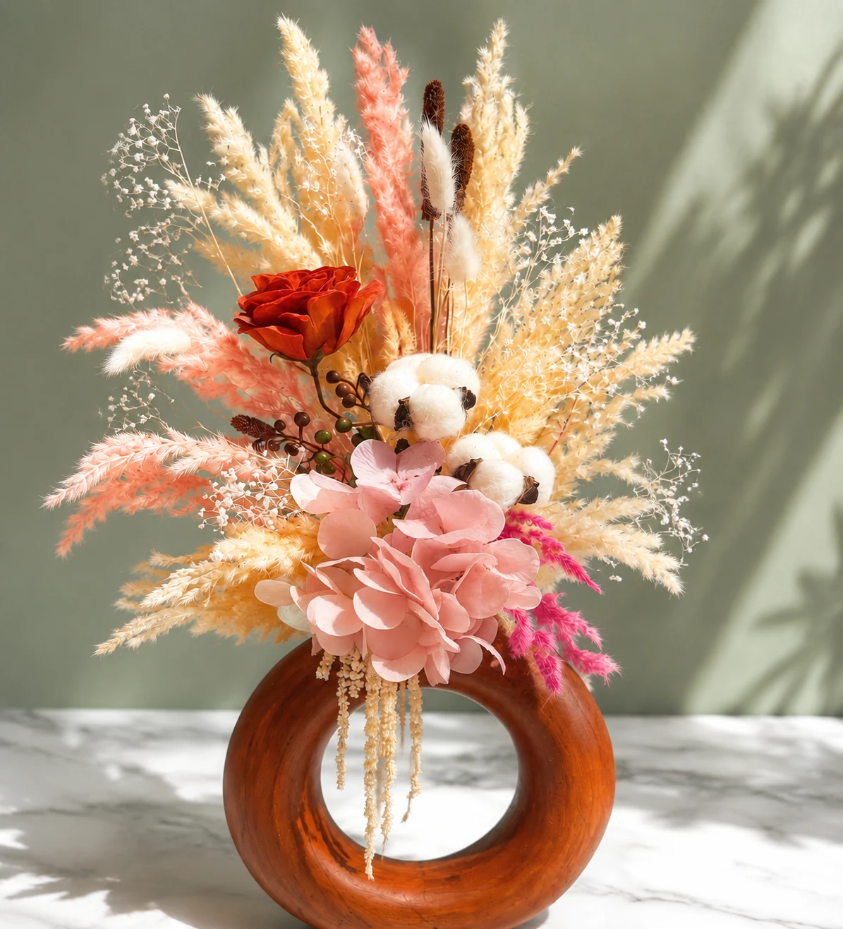 Corail solaire, composition en fleurs séchées corail et miel dans un vase circulaire brun à l’aspect bois